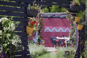 Wooden slats with view of pink wall and garden furniture 