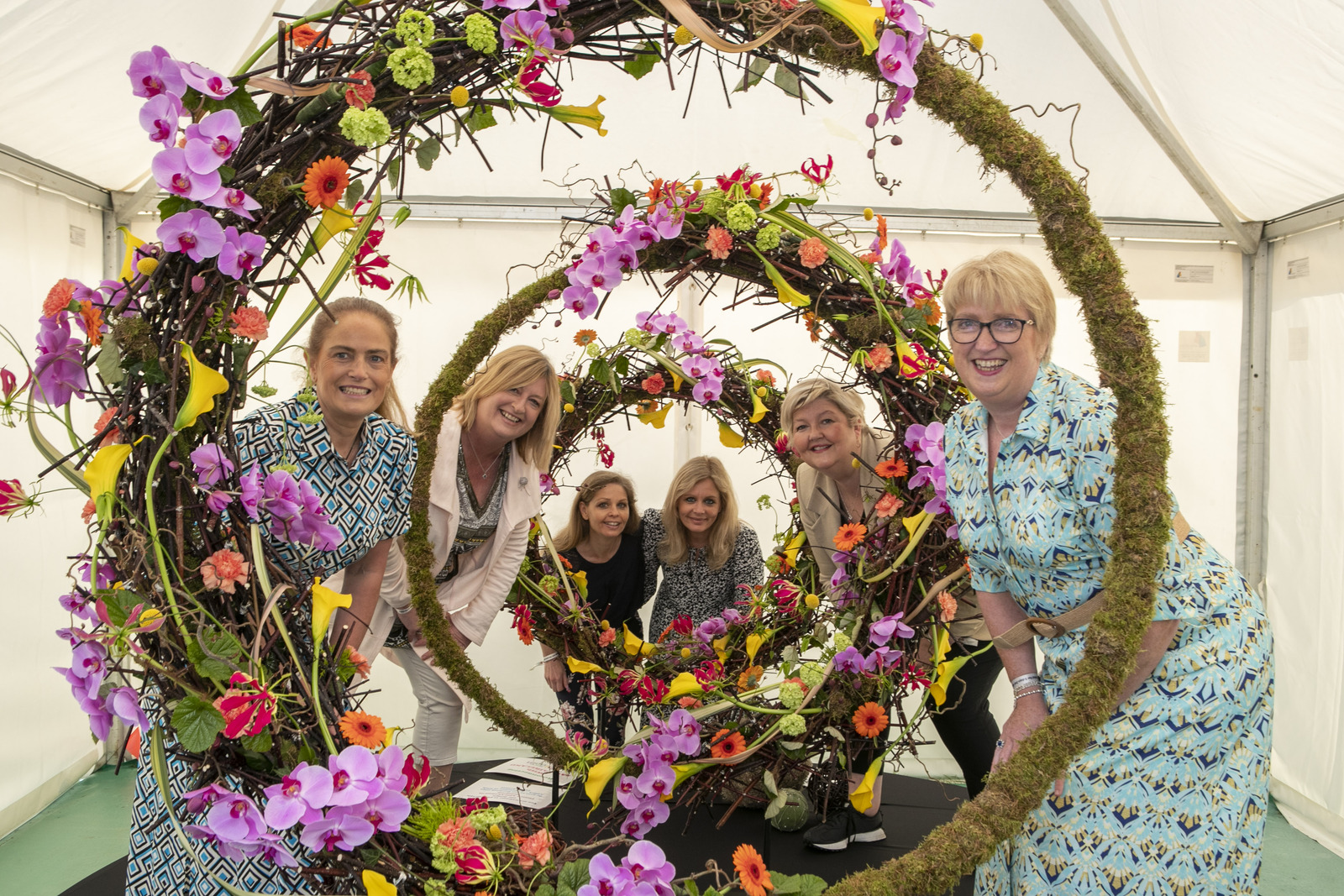 Artists gather around a piece of floral art as part of the AOIFA exhibit